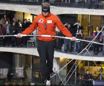 Sans harnais, les yeux bandés, un funambule relie Building